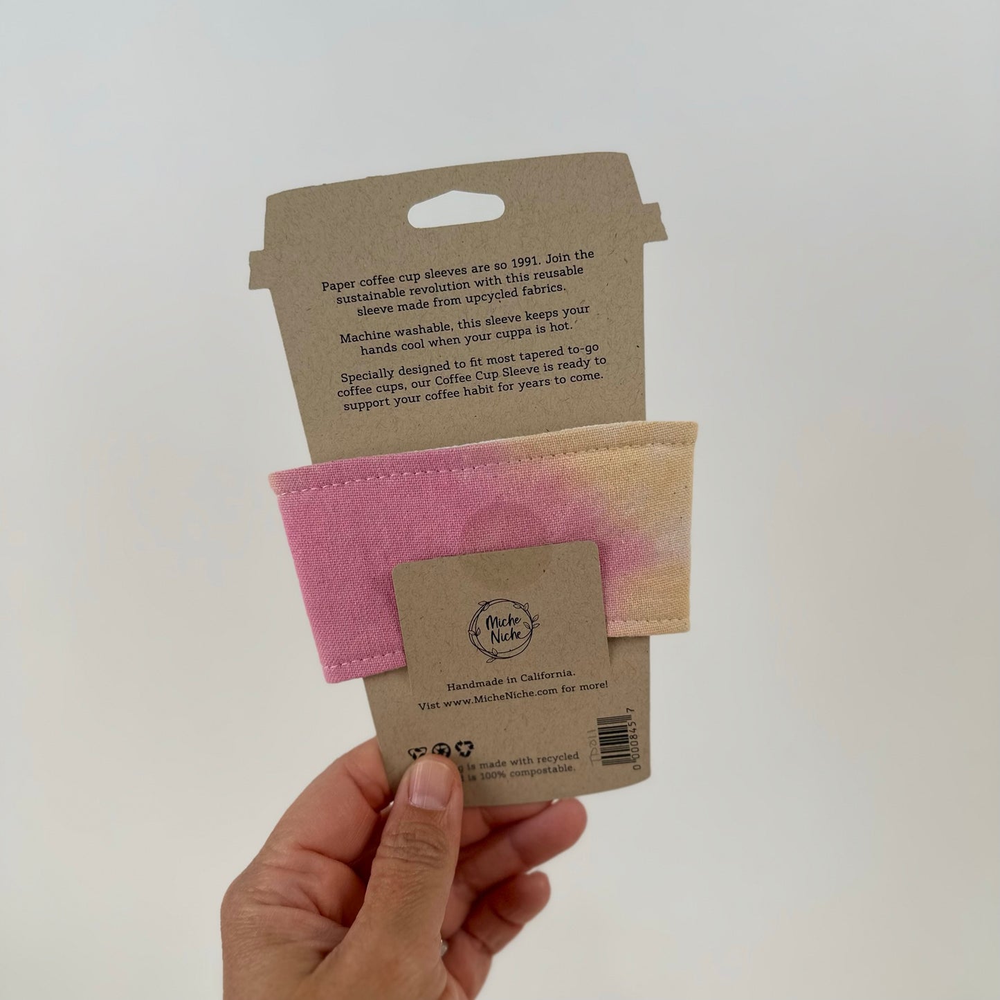Back view of a Miche Niche coffee cup sleeve in a hand dyed pastel yellow, green, and pink tie dye pattern