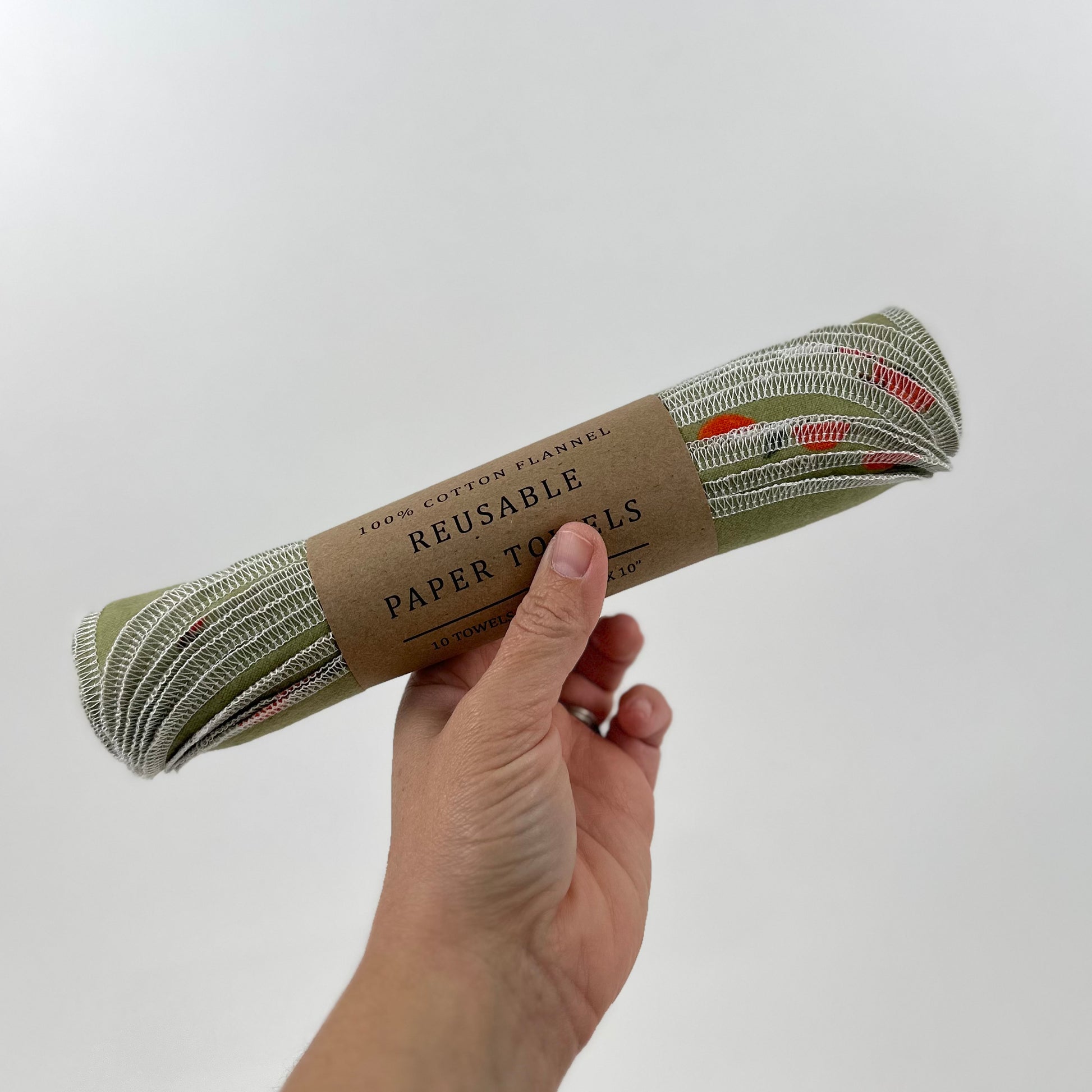 A packaged set of Miche Niche Reusable paper towels. The fabric is a sage green background with medium sized red apples.