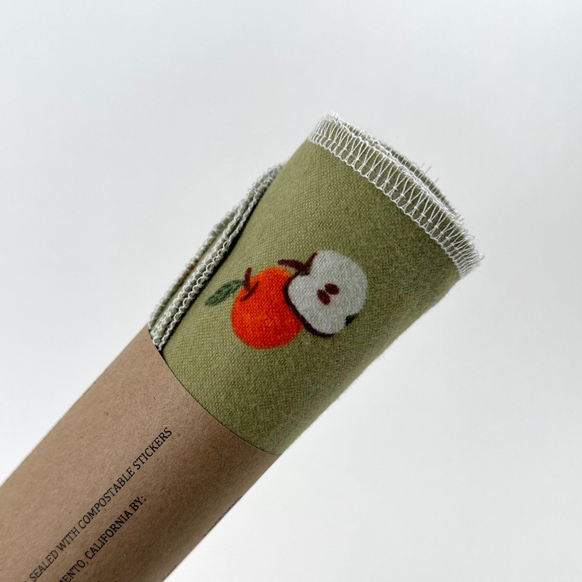A vibrant green felt roll with a juicy apple printed on it - part of the Miche Niche Reusable paper towels collection.
