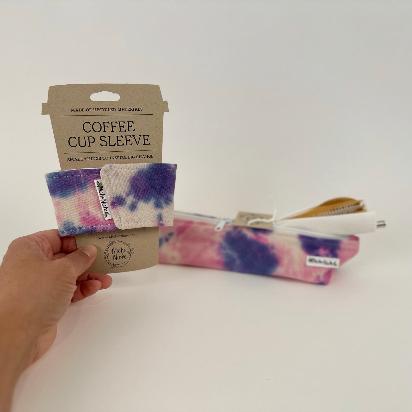 A matching set of a Niche Niche coffee cup sleeve and zipper pouch in a hand dyed blue and pink pattern.