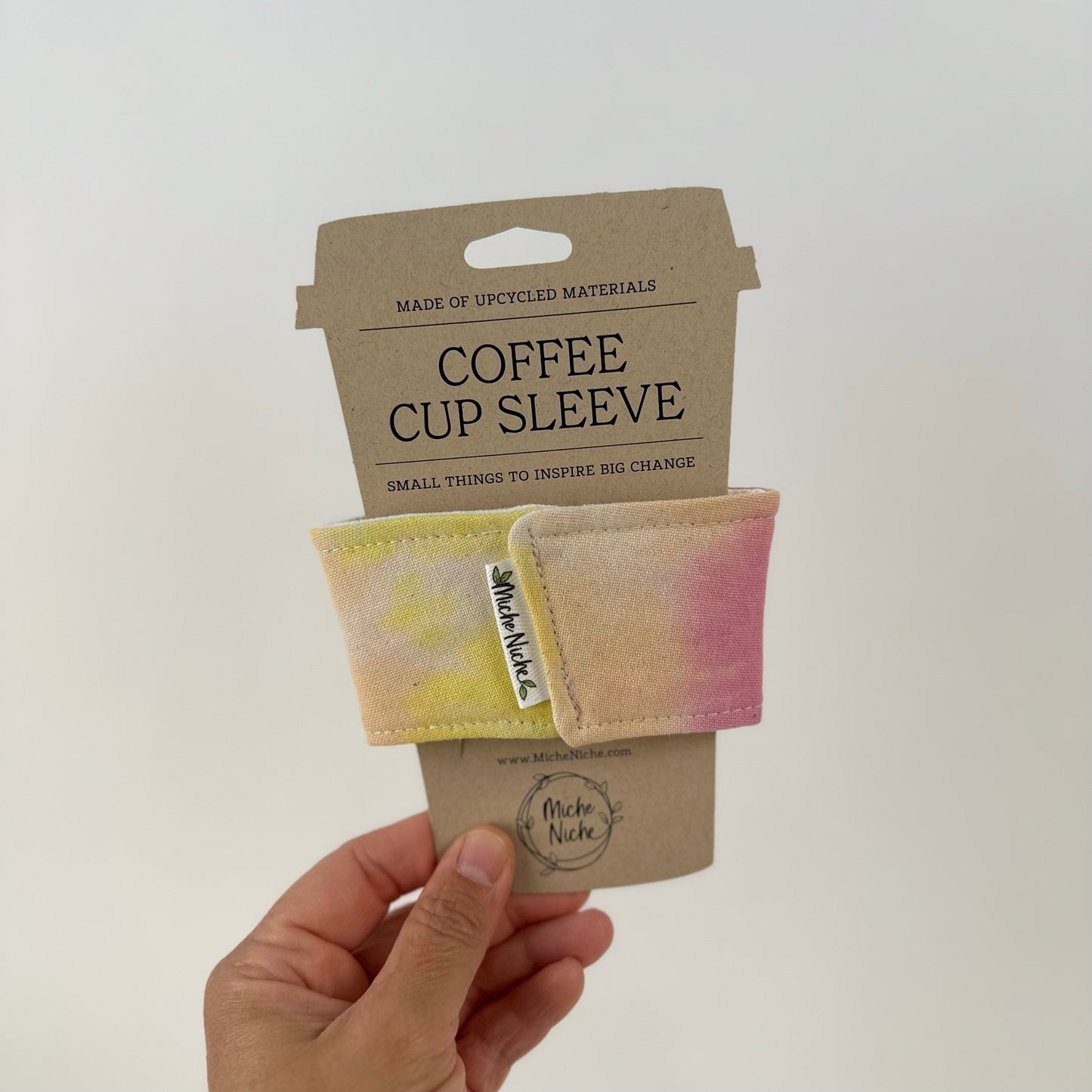 Miche Niche coffee cup sleeve in a hand dyed pastel yellow, green, and pink tie dye pattern