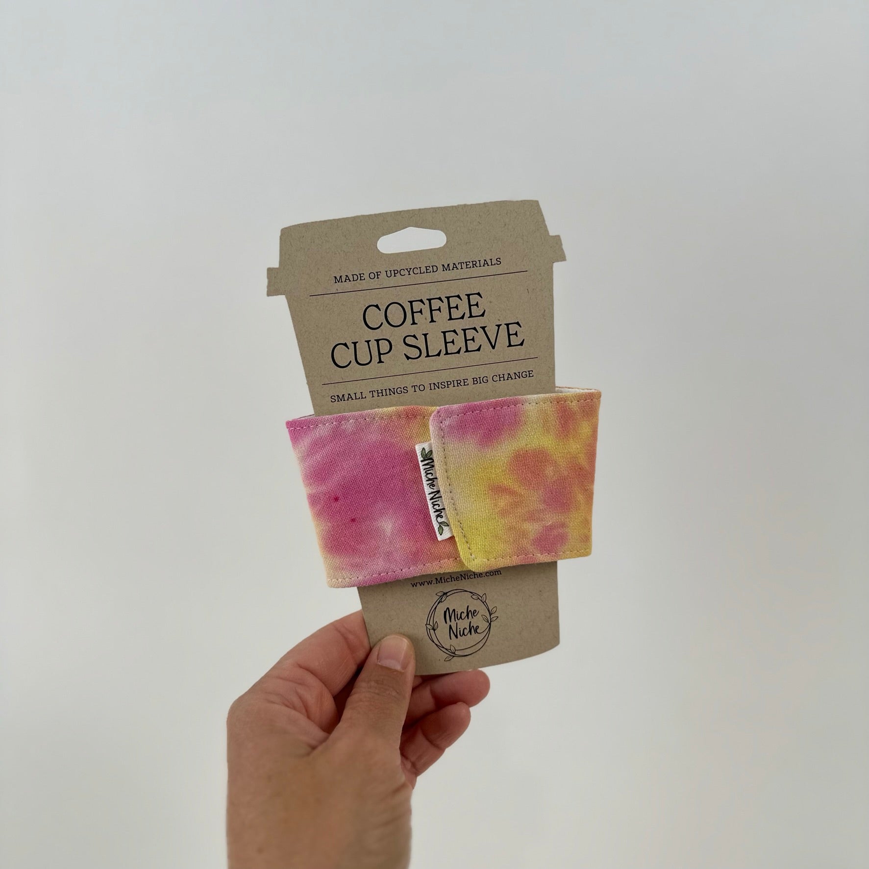 Front view of Miche Niche coffee cup sleeve in a hand dyed tie due pattern of pink, yellow, and fuchsia