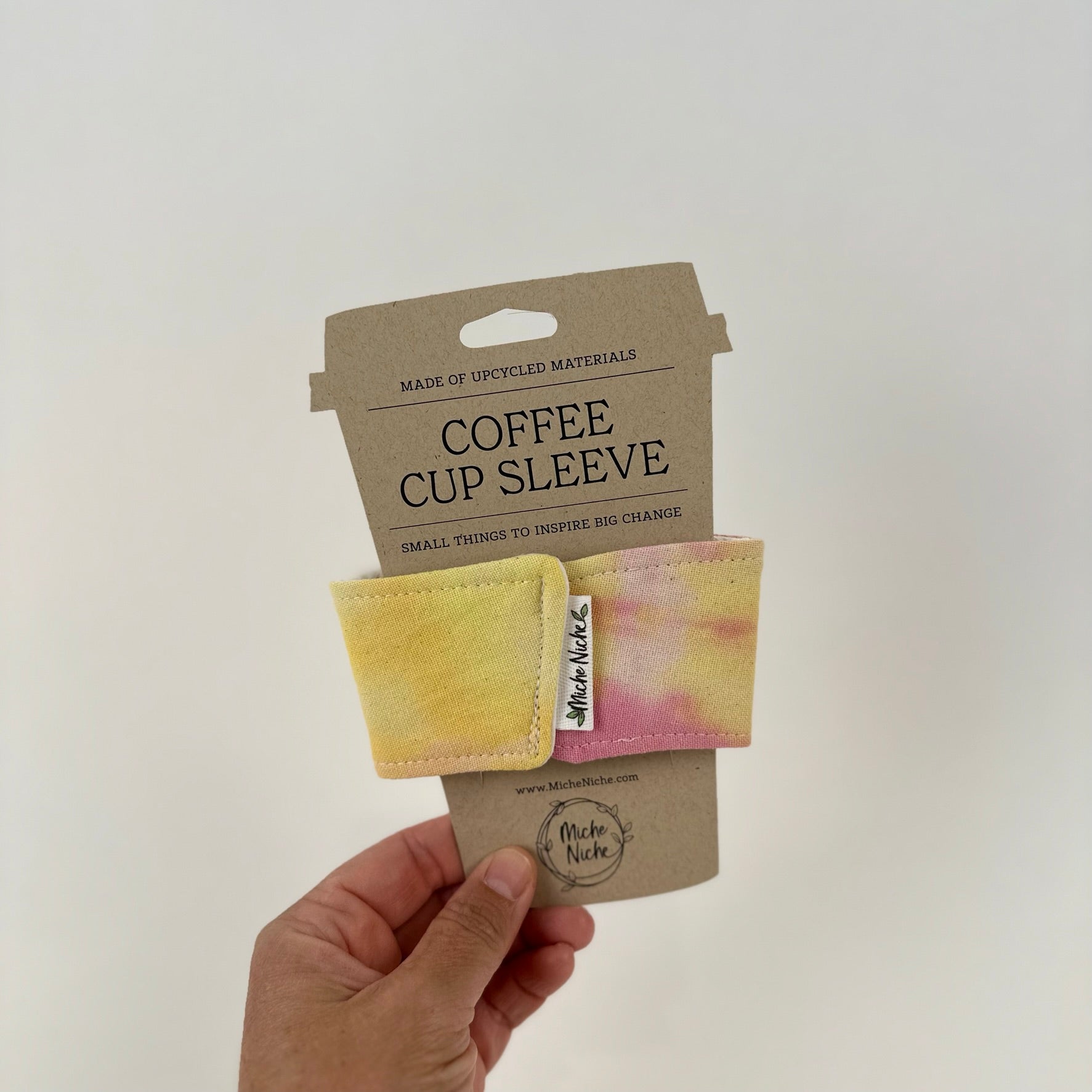 Miche Niche coffee cup sleeve in a hand dyed pink and yellow tie dye pattern