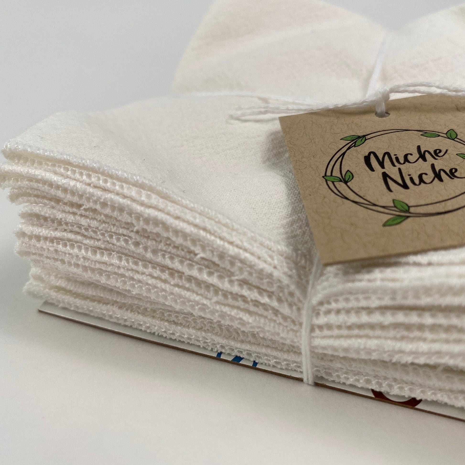 Closer view of the surged edge of Miche Niche every day reusable napkins with a white napkin and white edge stitching.